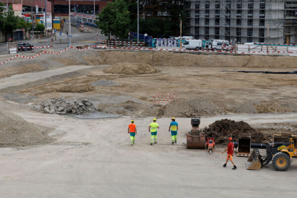 Vogelperspektive 4 Bauarbeiter gehen ueber das Baugelaende