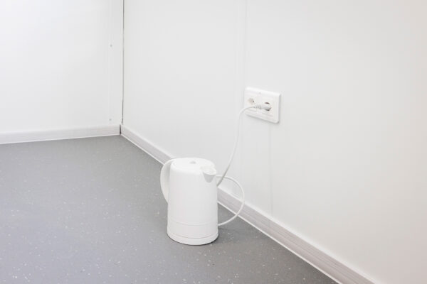 In Steckdose eingesteckter Wasserkocher auf dem Boden