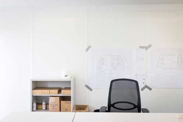 Arbeitsplatz Regal, Schutzhelm und Bauplänen an der Wand