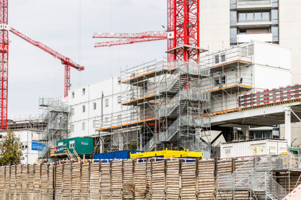 Weisse Containeranlage mit Treppentürmen und Baustellenkränen auf dem FORUM-UZH-Areal