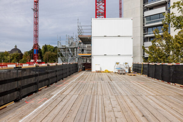 Holzplattform vor der weissen Containeranlage