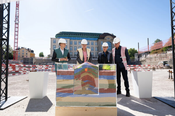 Kleine Skulptur in einem Gefäss, vollständig von farbigem Sand bedeckt.