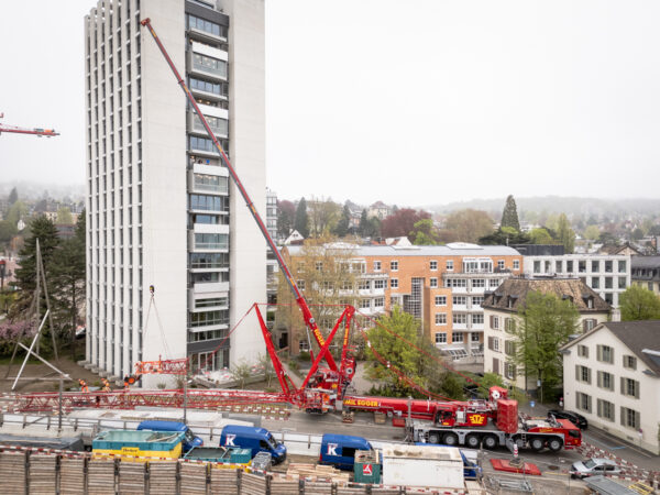 Pneukran montiert ein Segment eines Turmdrehkrans neben dem Careum Hochhaus.