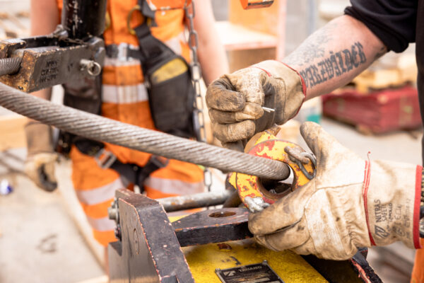 Detailaufnahme der Sicherung eines Stahlseils an einem Kranelement während der Montage.
