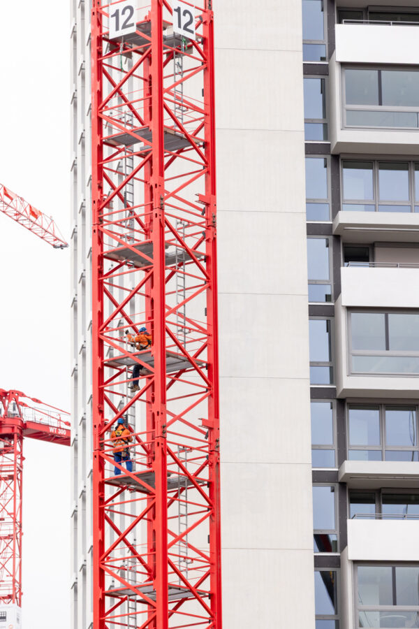 Zwei Bauarbeiter steigen im Turm eines Turmdrehkrans während des Aufbaus neben dem Careum Hochhaus.